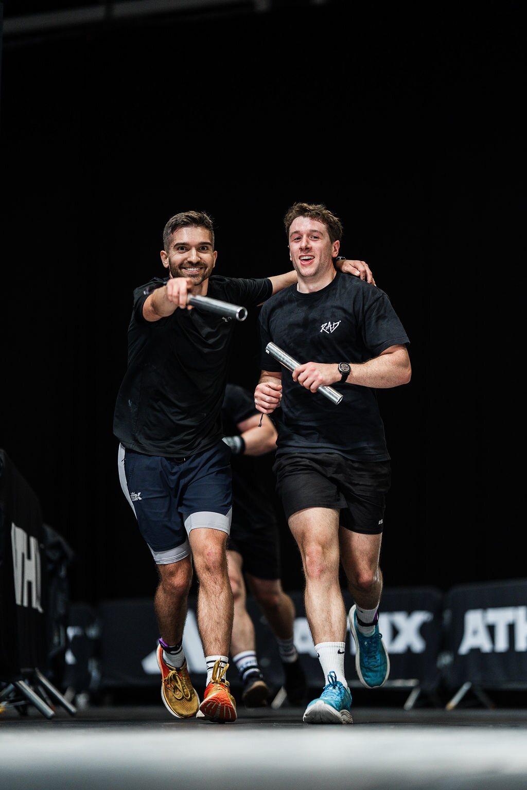 Two athletes run side by side carrying batons in the Endurance Zone